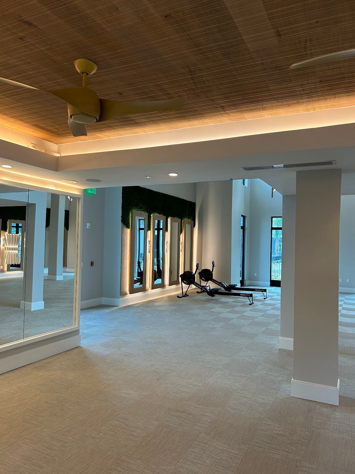 A large room with a lot of mirrors and a ceiling fan.