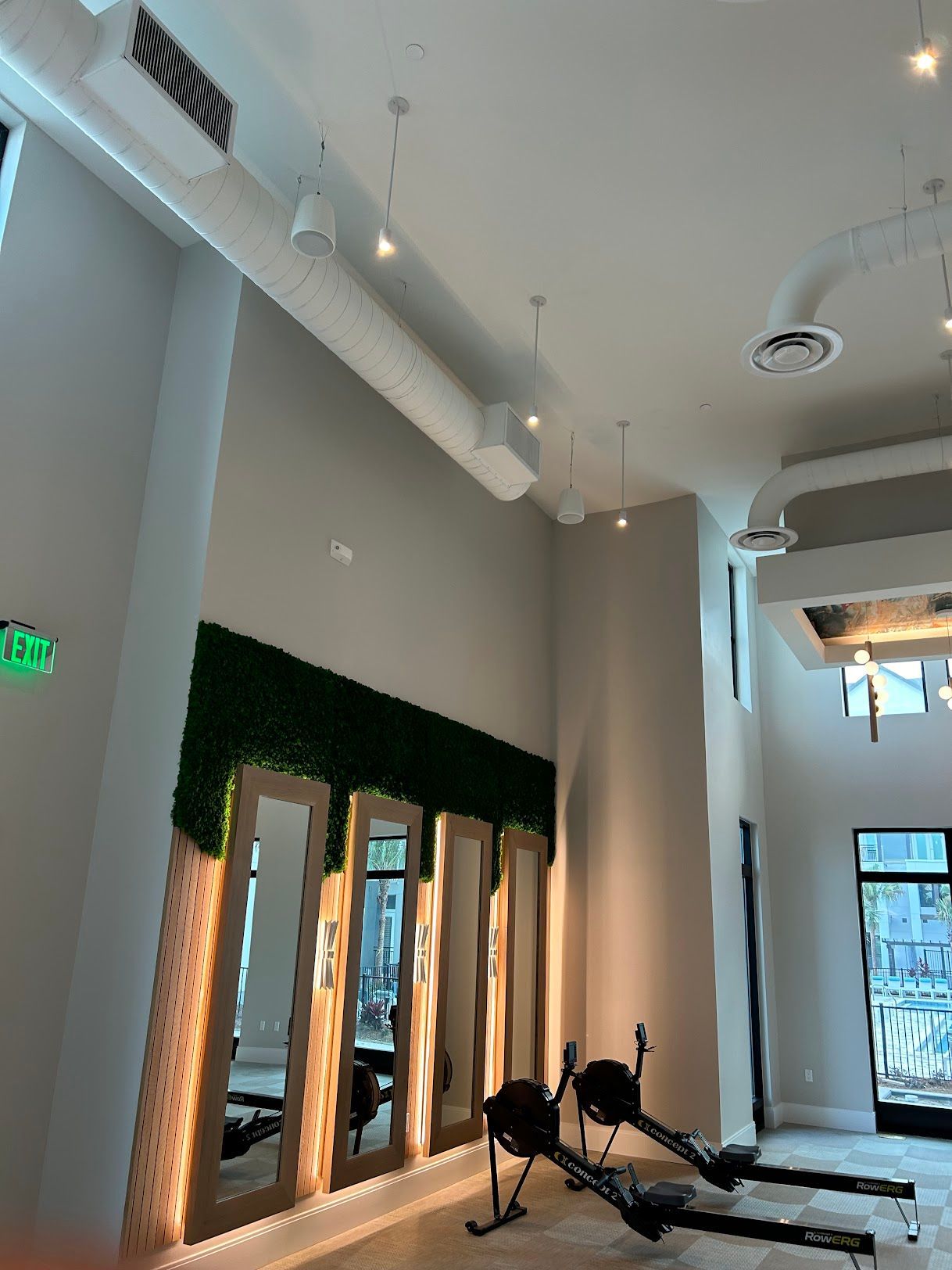 A gym with a lot of mirrors and a green exit sign