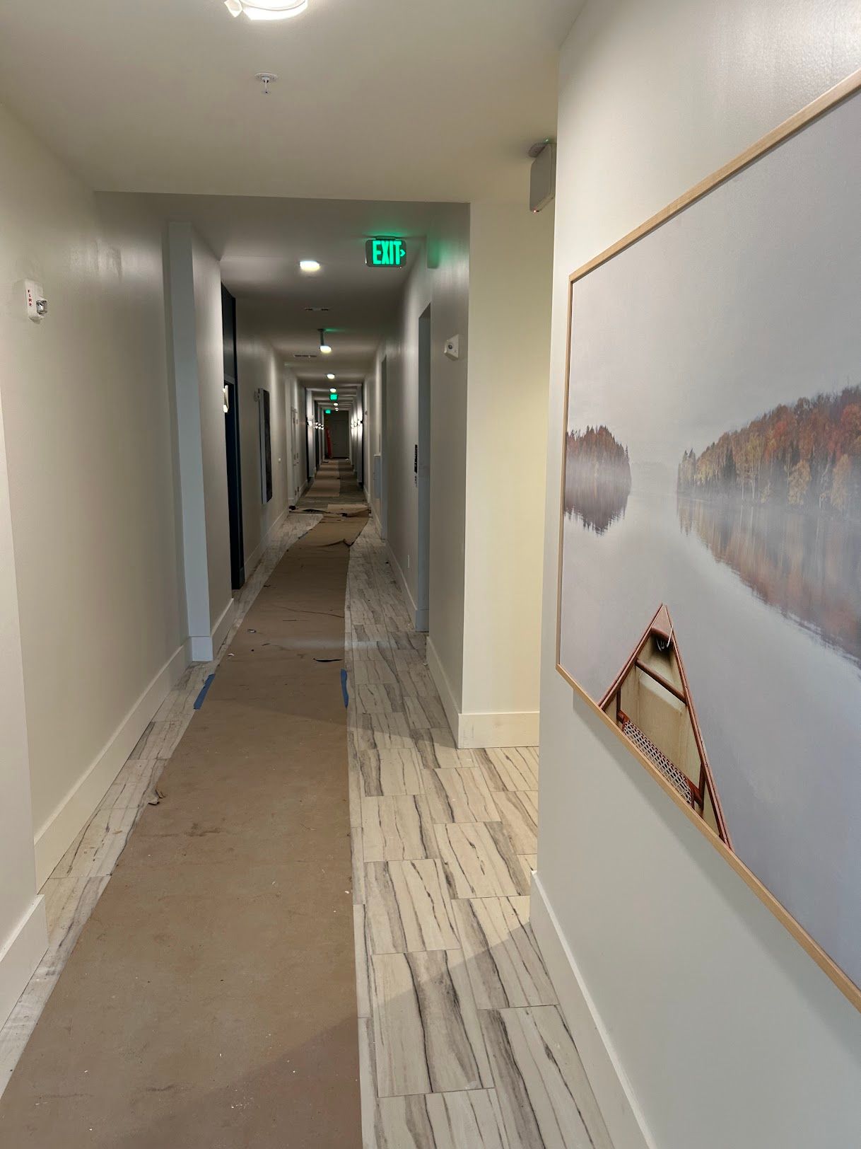 A long hallway with a picture of a lake on the wall.