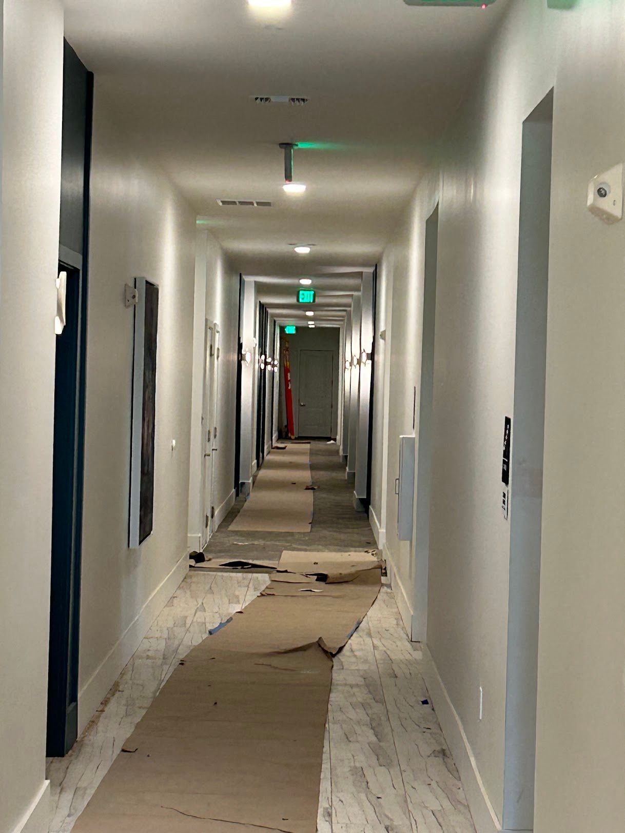 A long hallway with a green exit sign on the ceiling