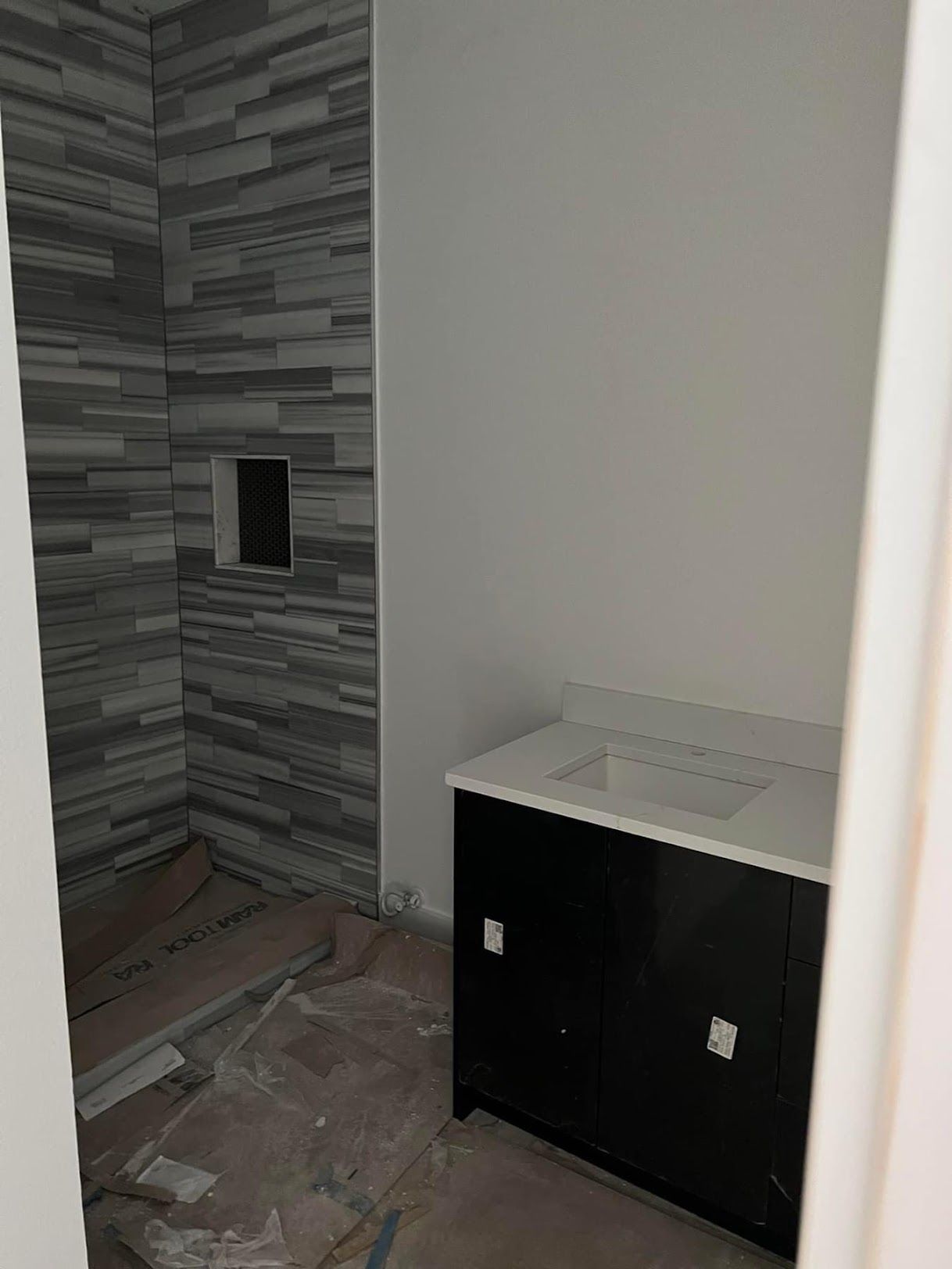 A bathroom with a sink and a walk in shower under construction.