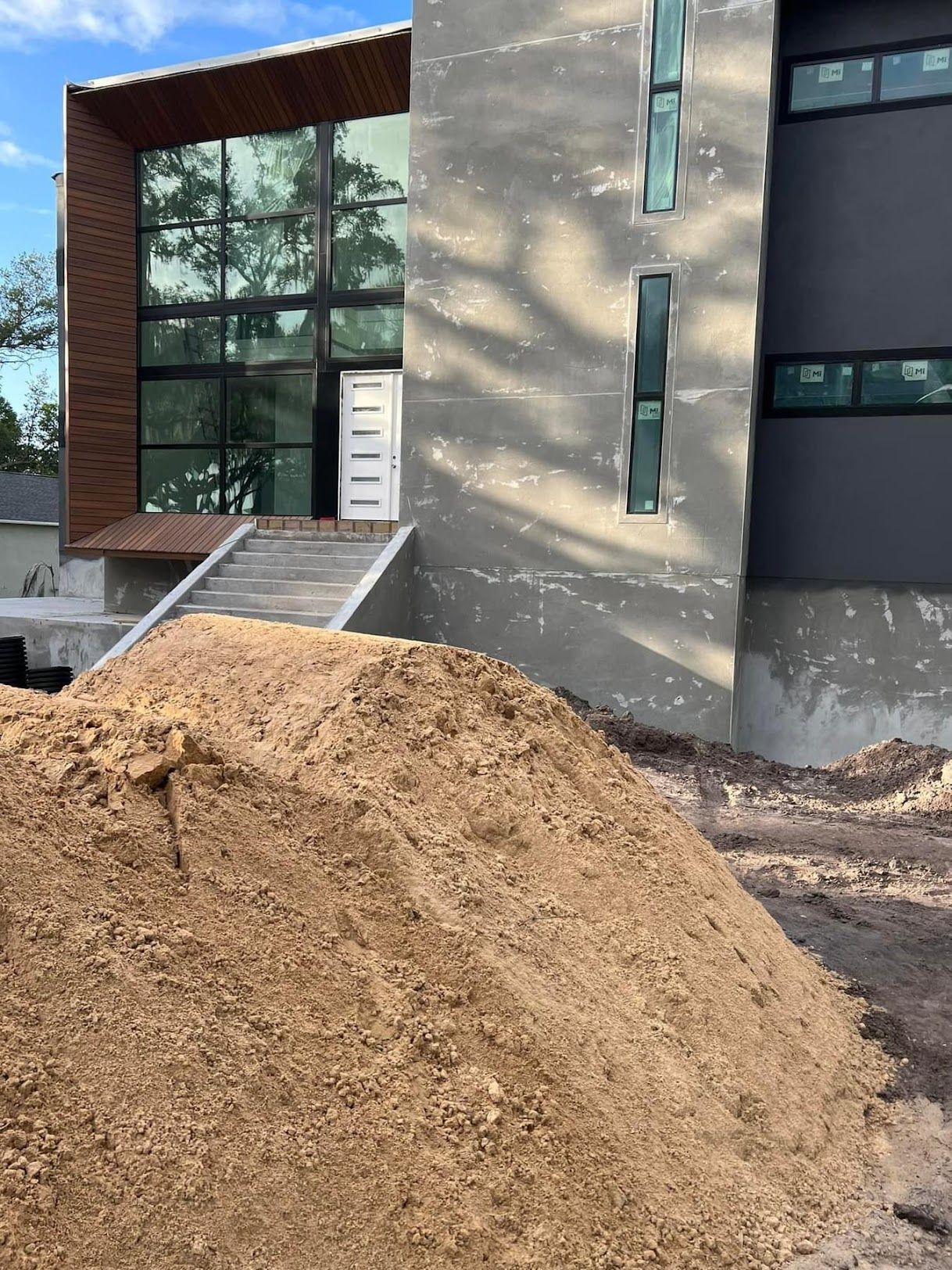 A large pile of dirt is in front of a building under construction.