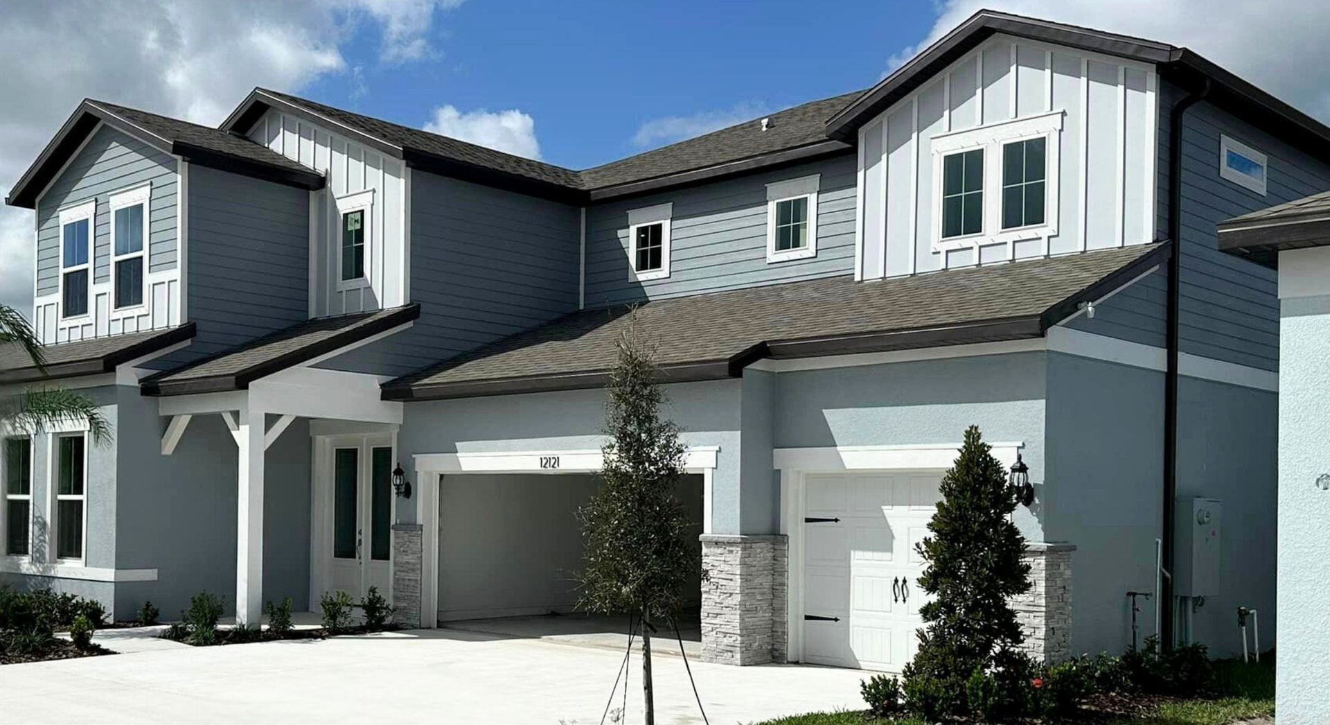 A large gray and white house with a brown roof