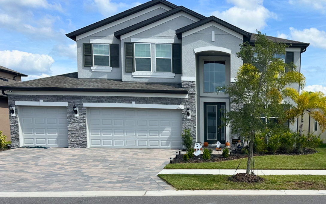 A large house with two garages and a tree in front of it.