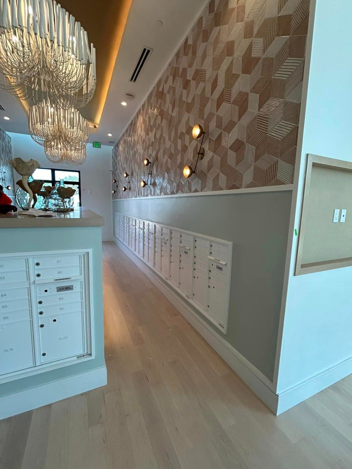 A long hallway with lots of mailboxes and a chandelier hanging from the ceiling.