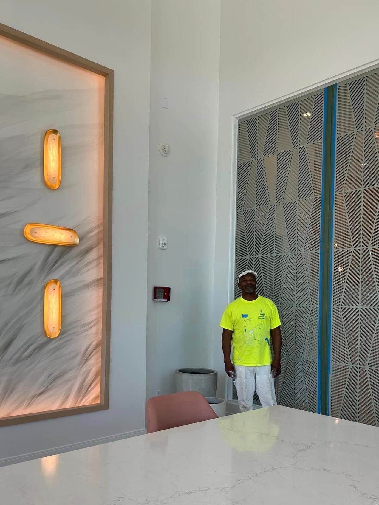 A man in a yellow shirt is standing in a room next to a table.