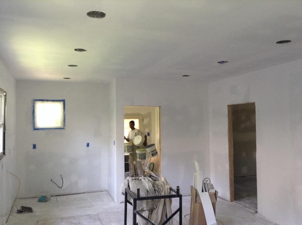 A man is standing in a room with white walls.