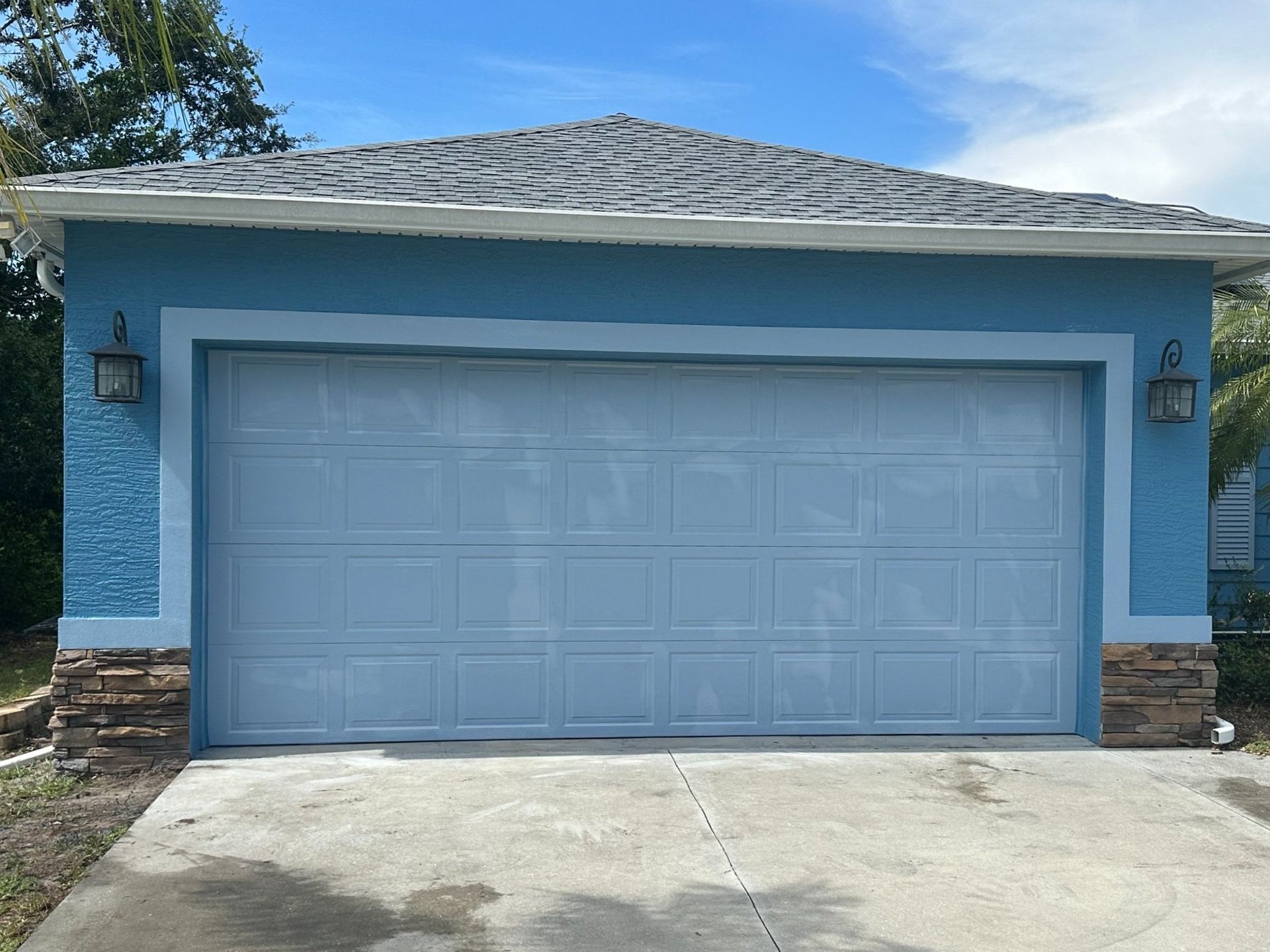 A blue house with a white garage door and a gray roof.