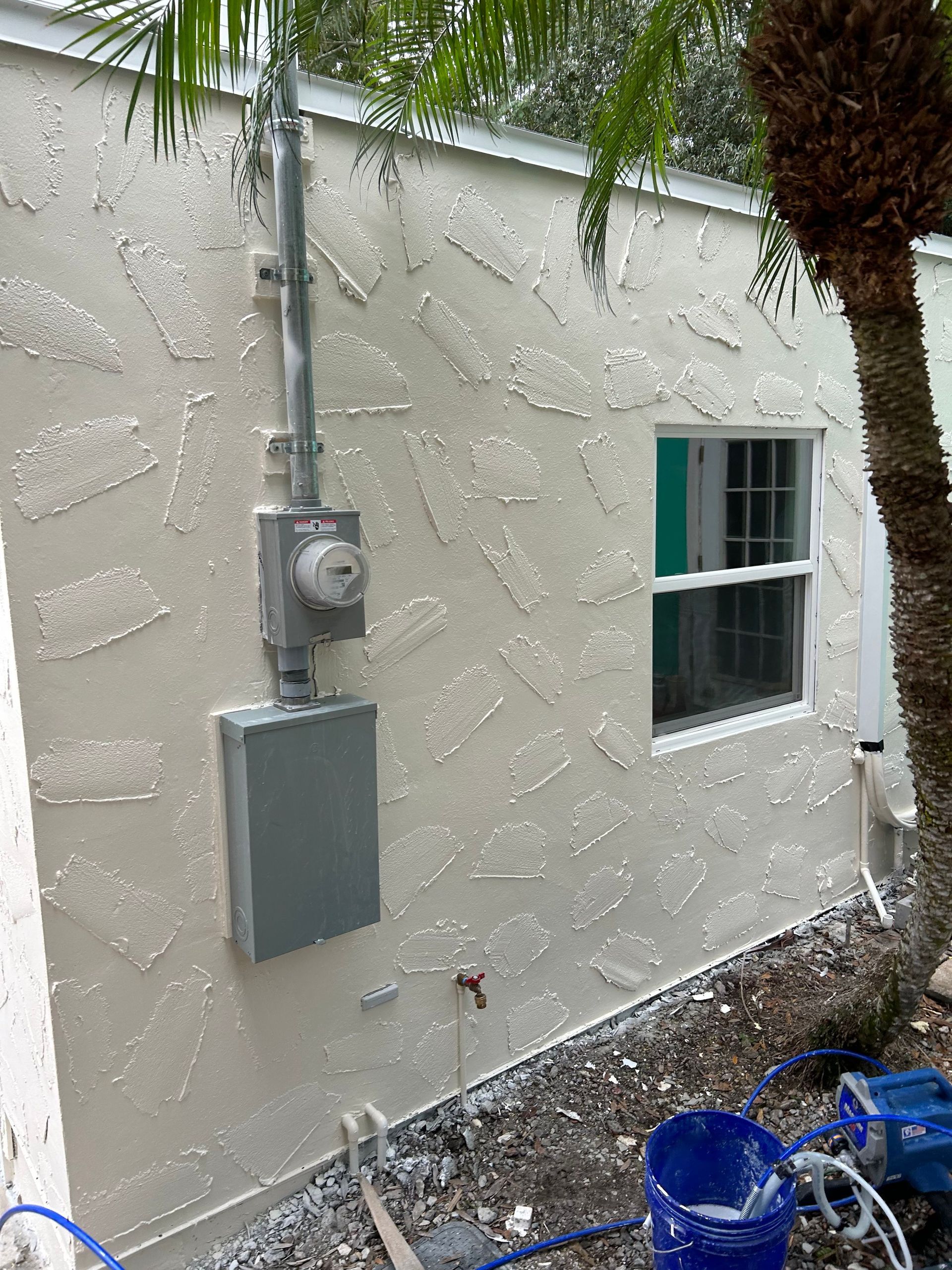 A white house with a window and a meter box on the side.