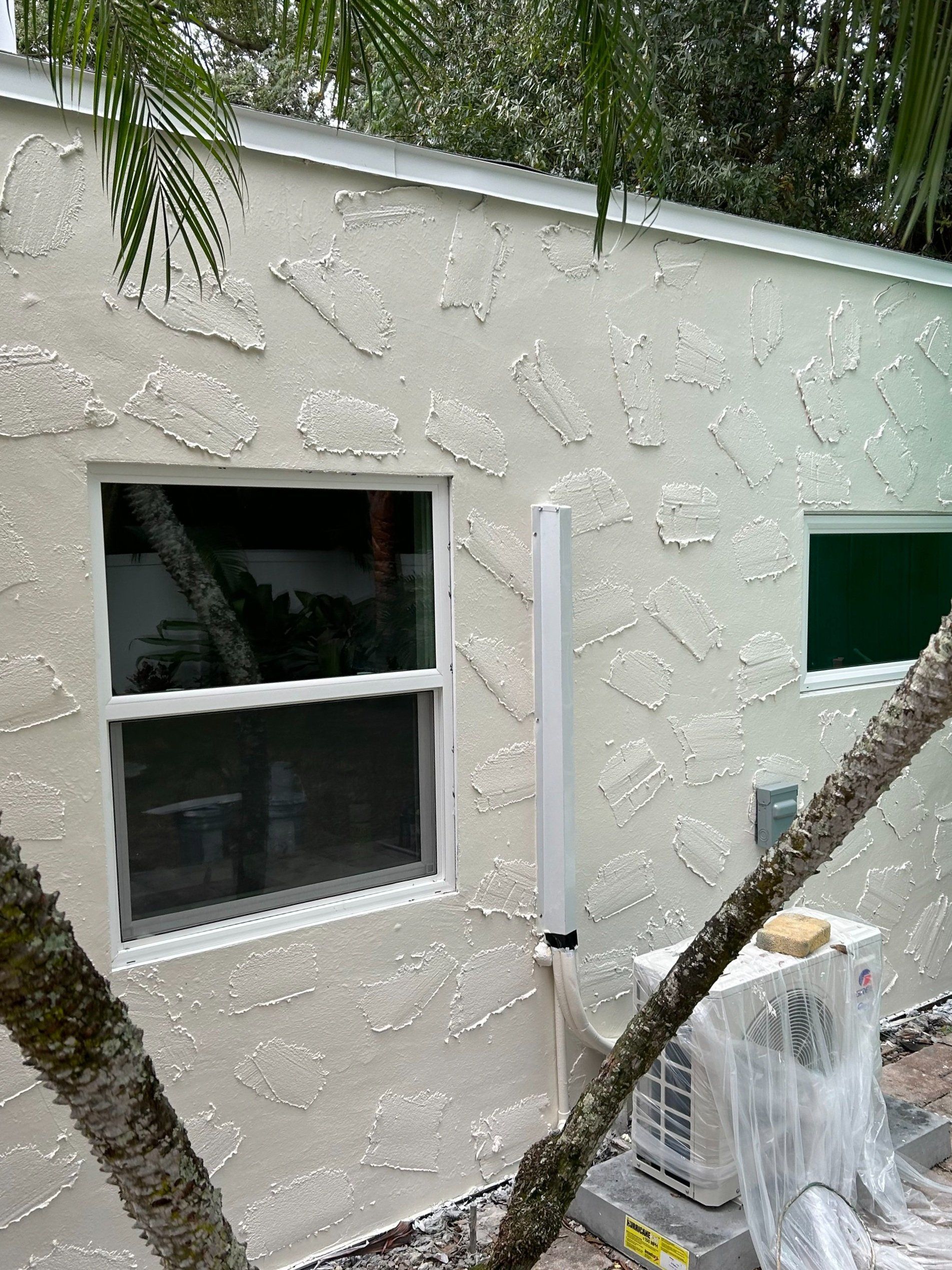 A white house with a window and air conditioner on the side.