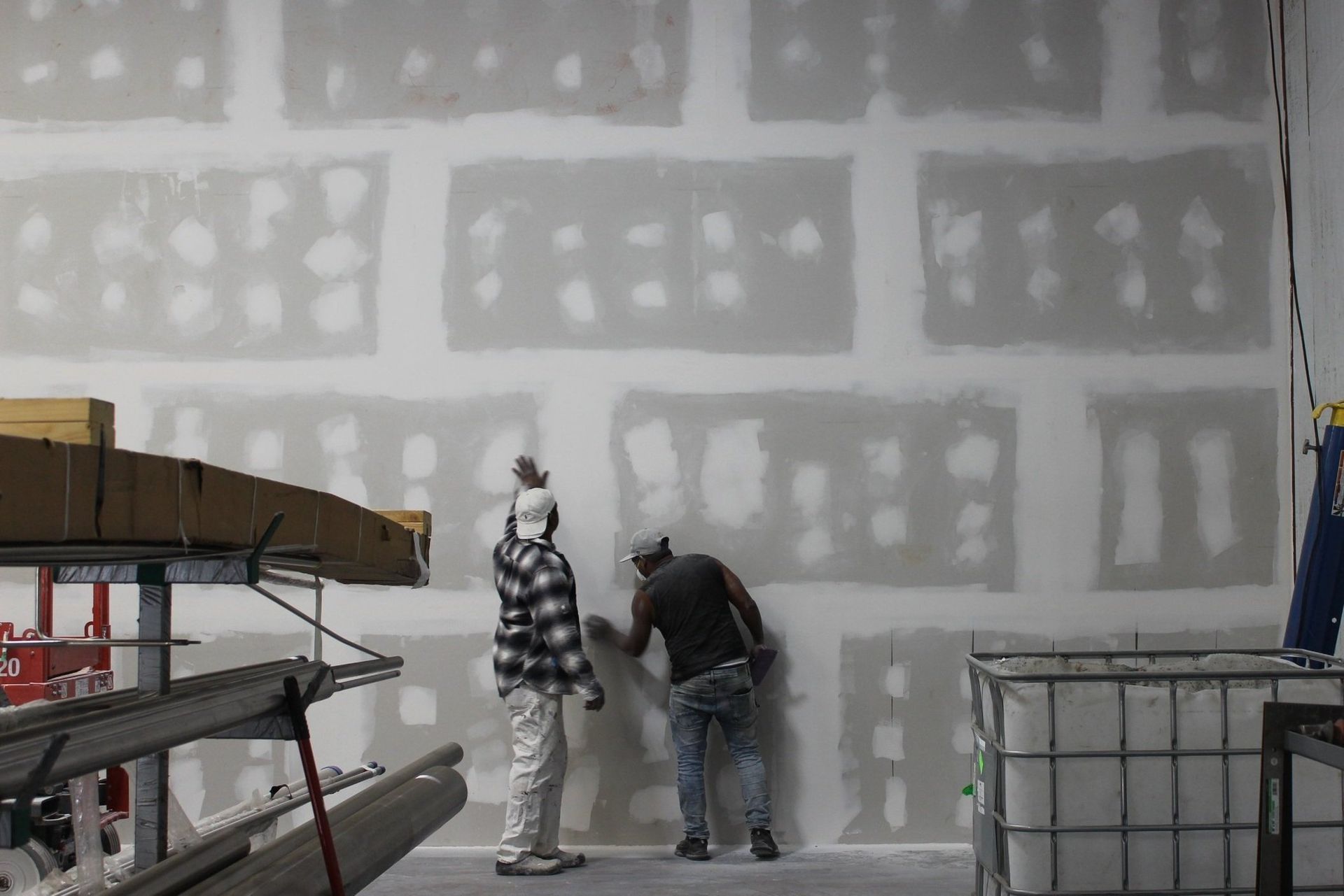Two men are working on a wall in a building.
