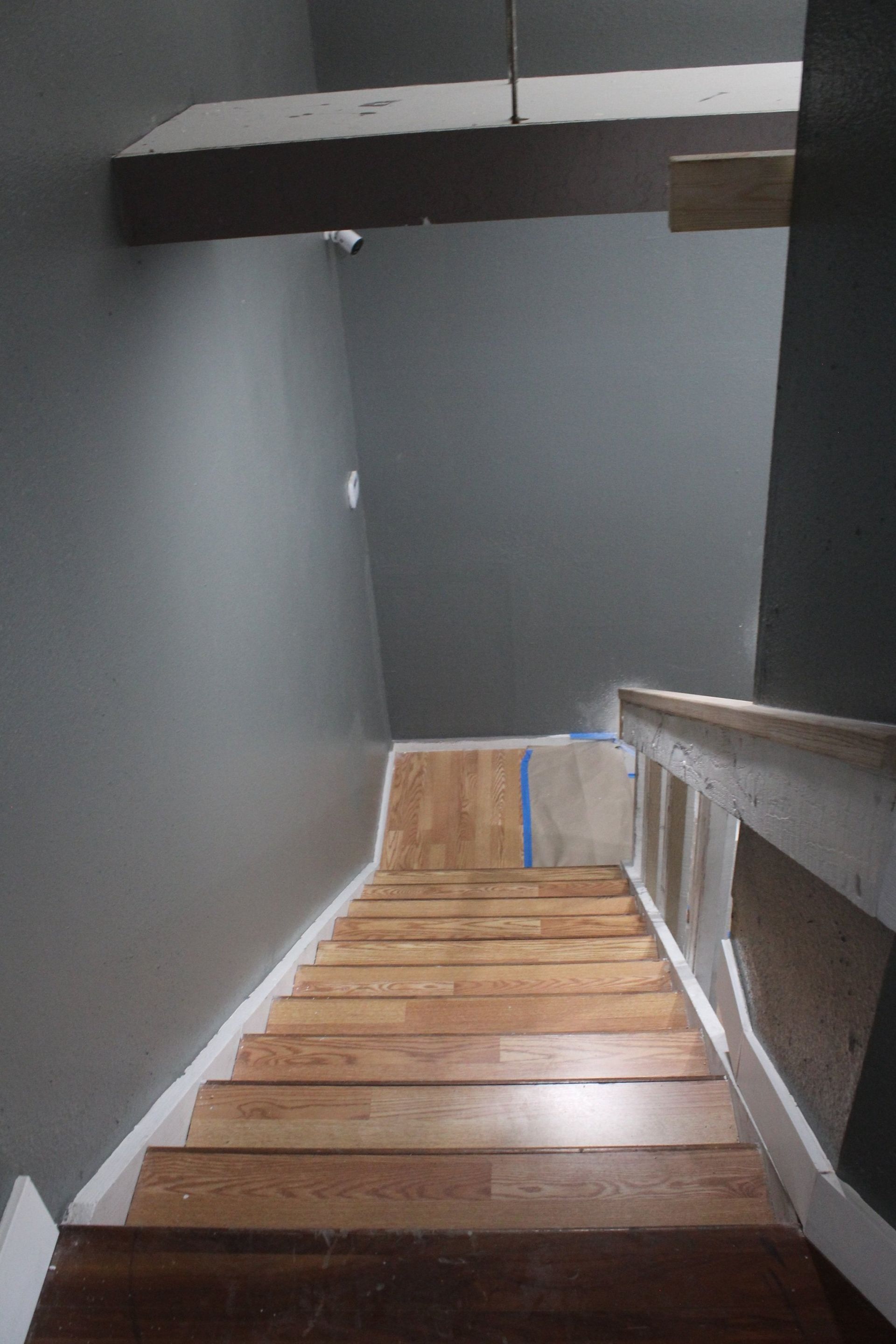 A wooden staircase with a railing and a gray wall