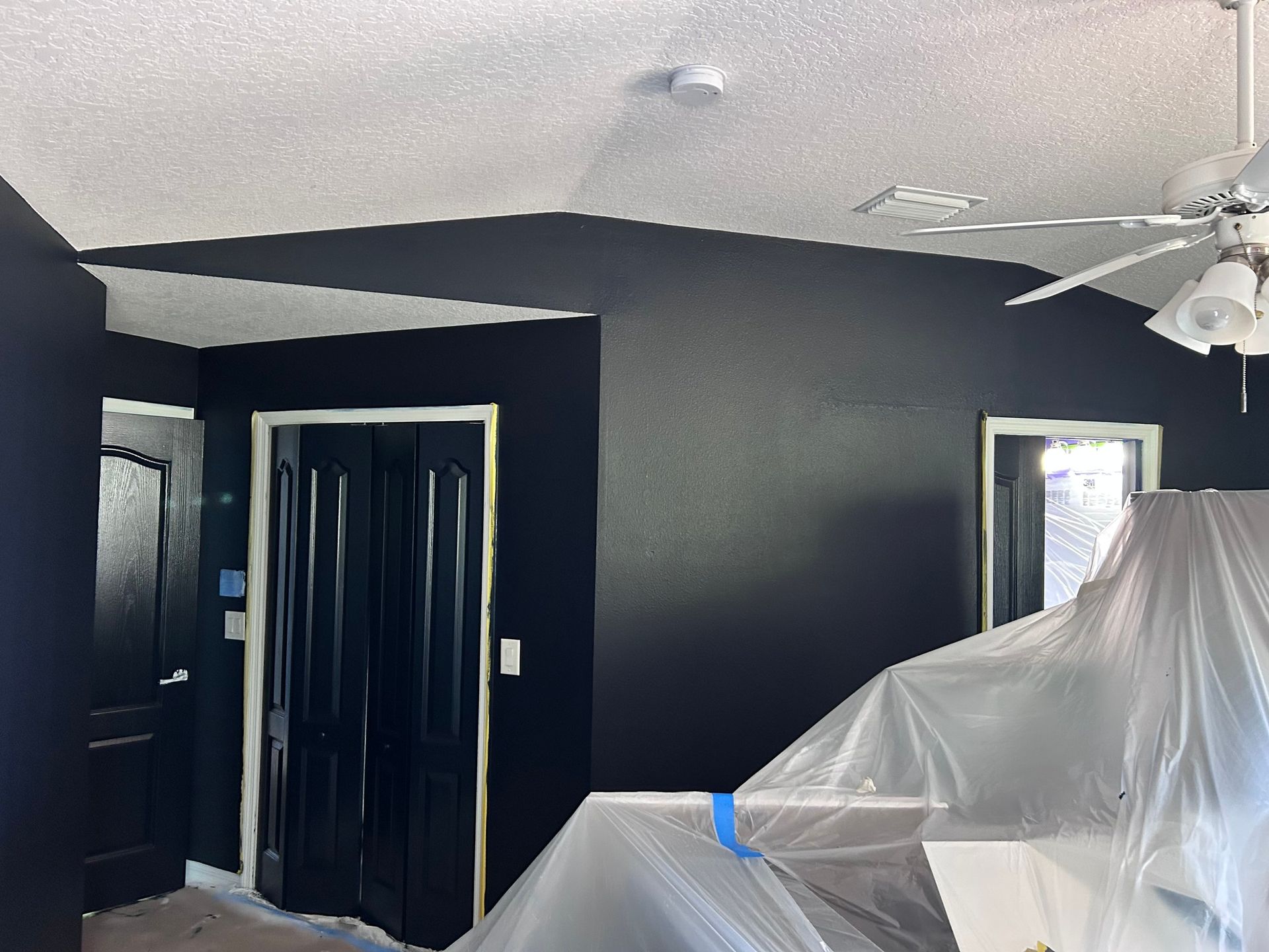 A room with black walls and a ceiling fan