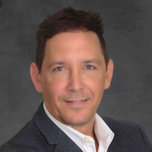 A man is holding a dog in his arms and the dog is wearing a sweater.