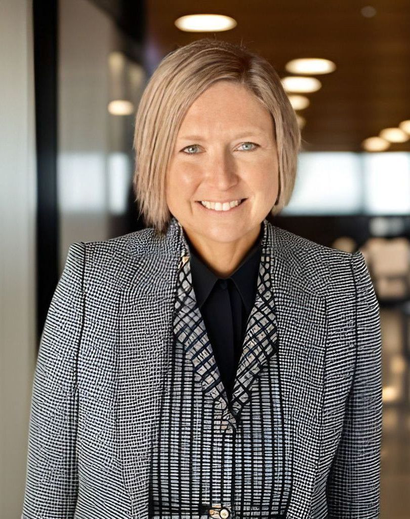 A woman in a plaid jacket and black shirt is smiling for the camera.