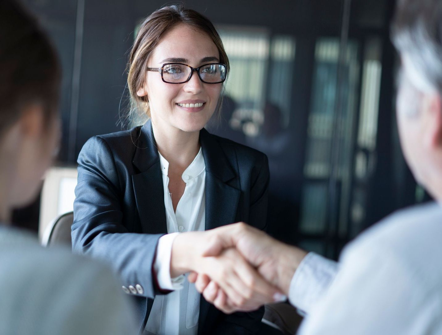 A woman is shaking hands with a man during a job interview.