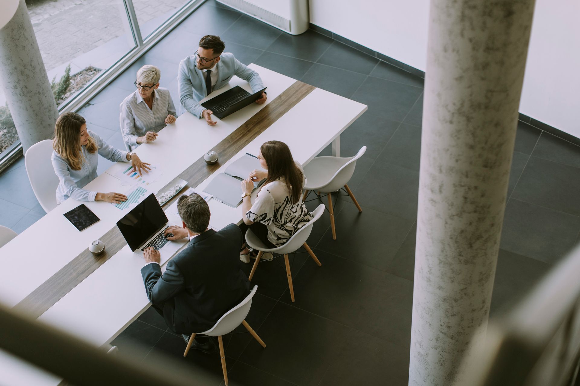 A group of people are sitting around a table with laptops.