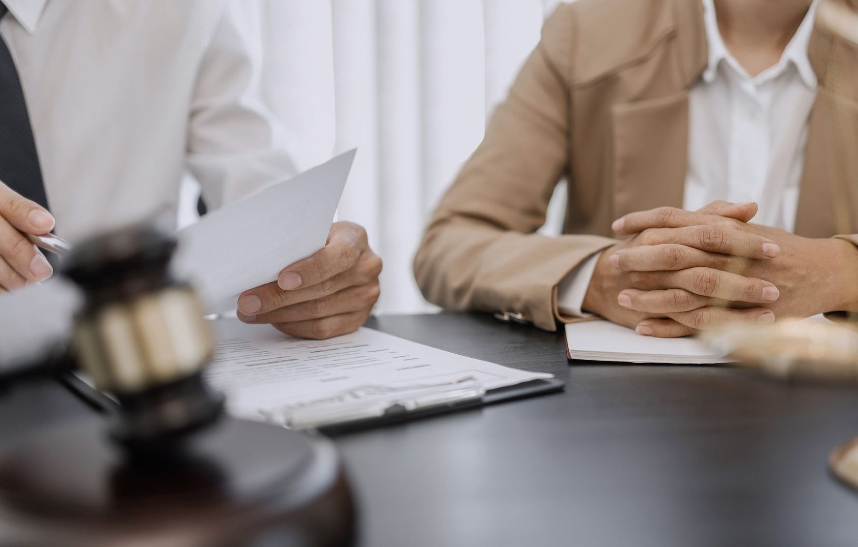 A man is holding a piece of paper in front of two people sitting at a table.