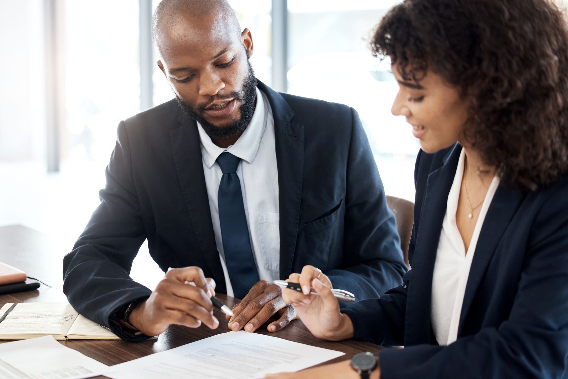 A man and a woman are sitting at a table looking at a piece of paper.