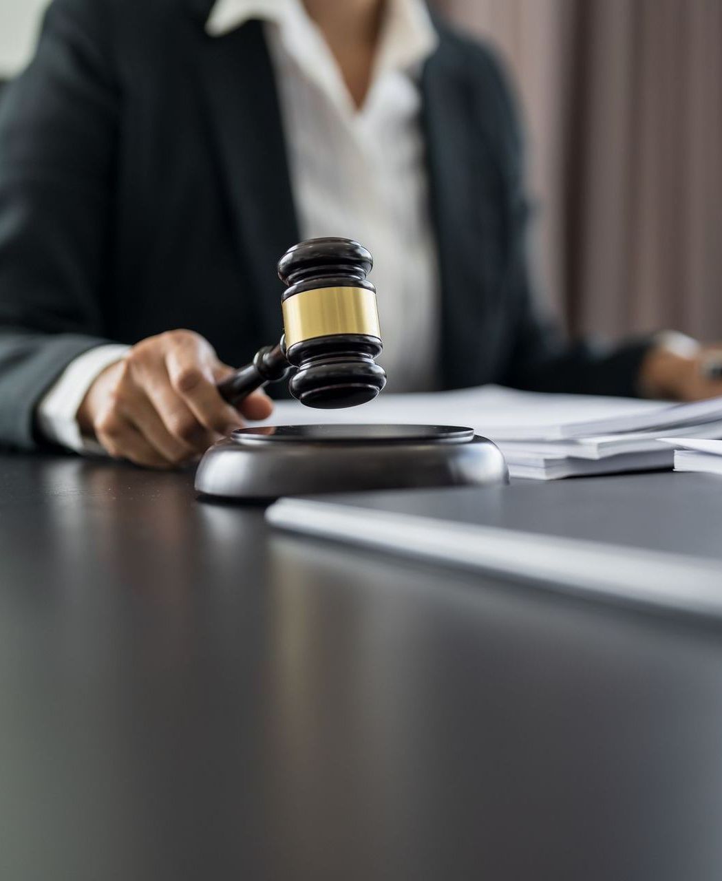 A judge is sitting at a table holding a wooden gavel.