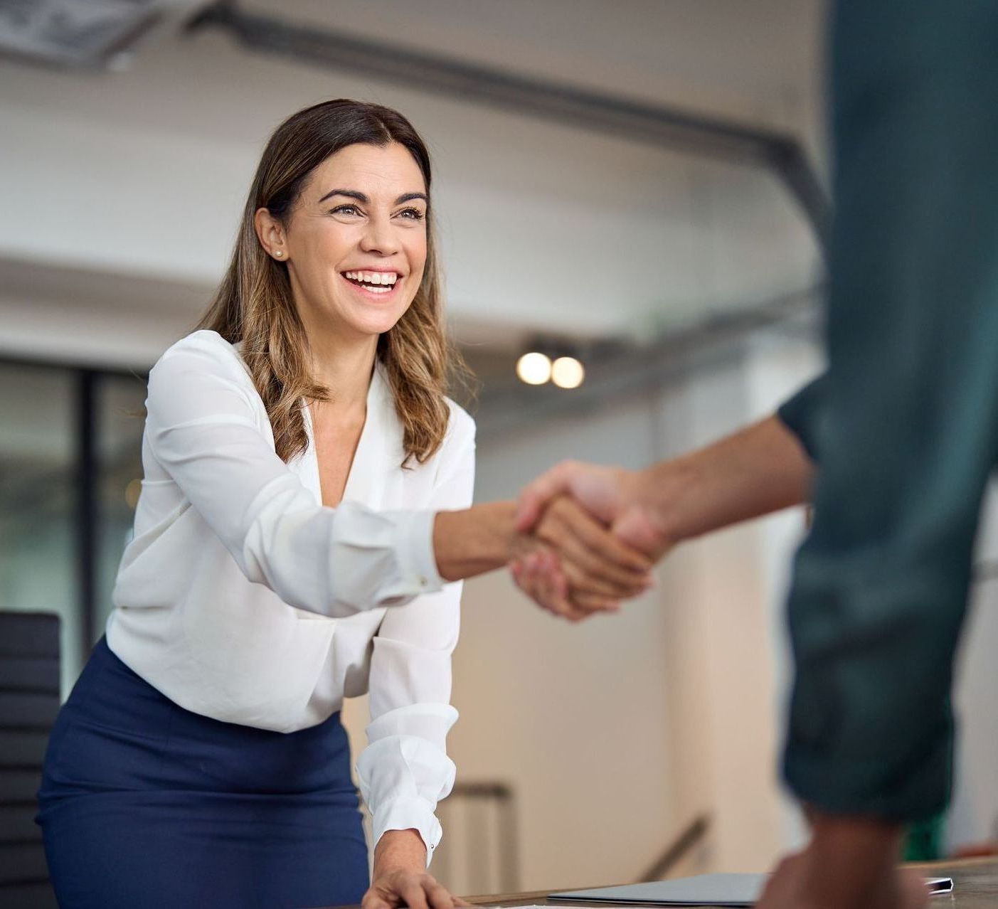 A woman is shaking hands with a man in an office.