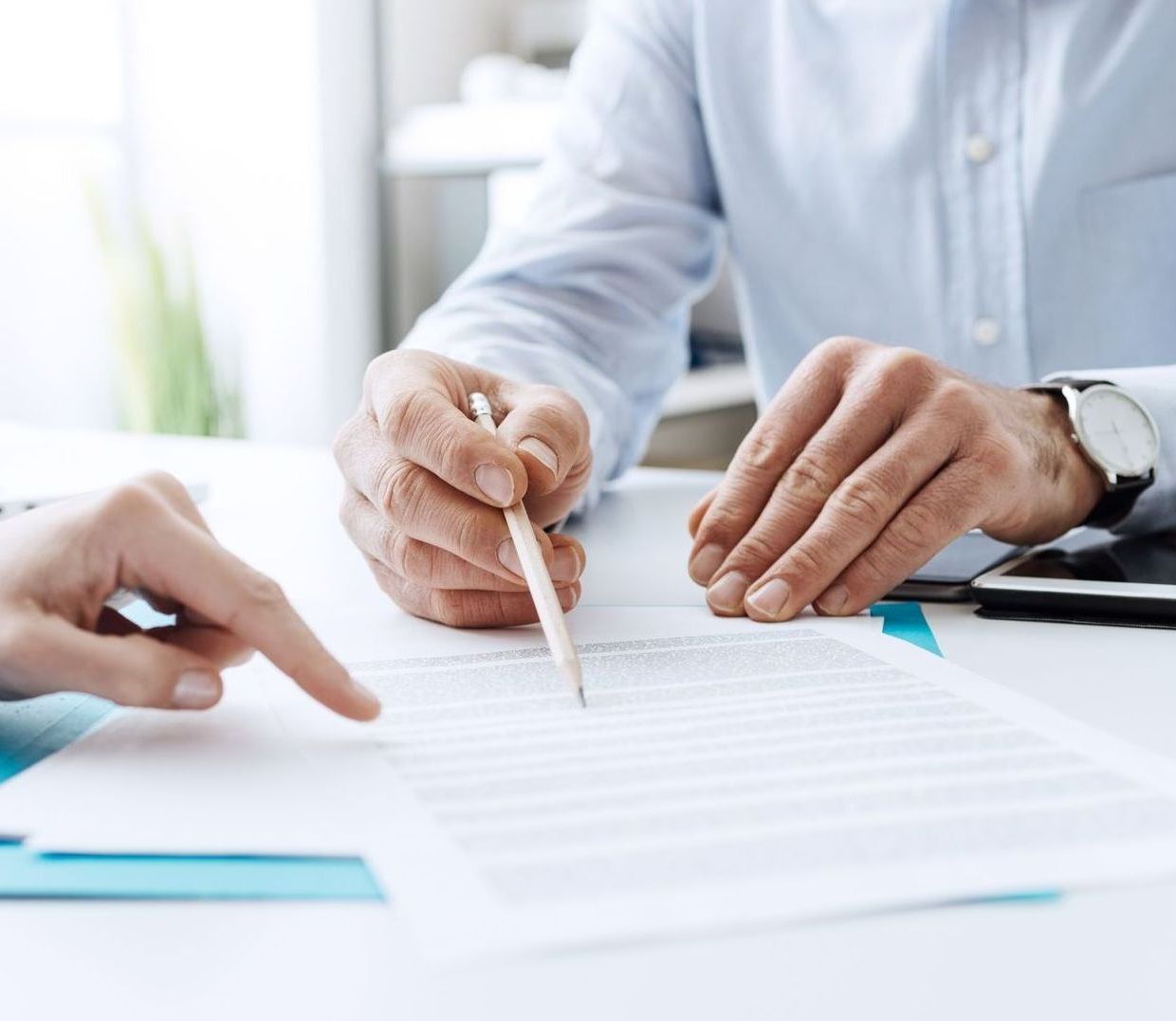 A man is writing on a piece of paper while another person points at it.