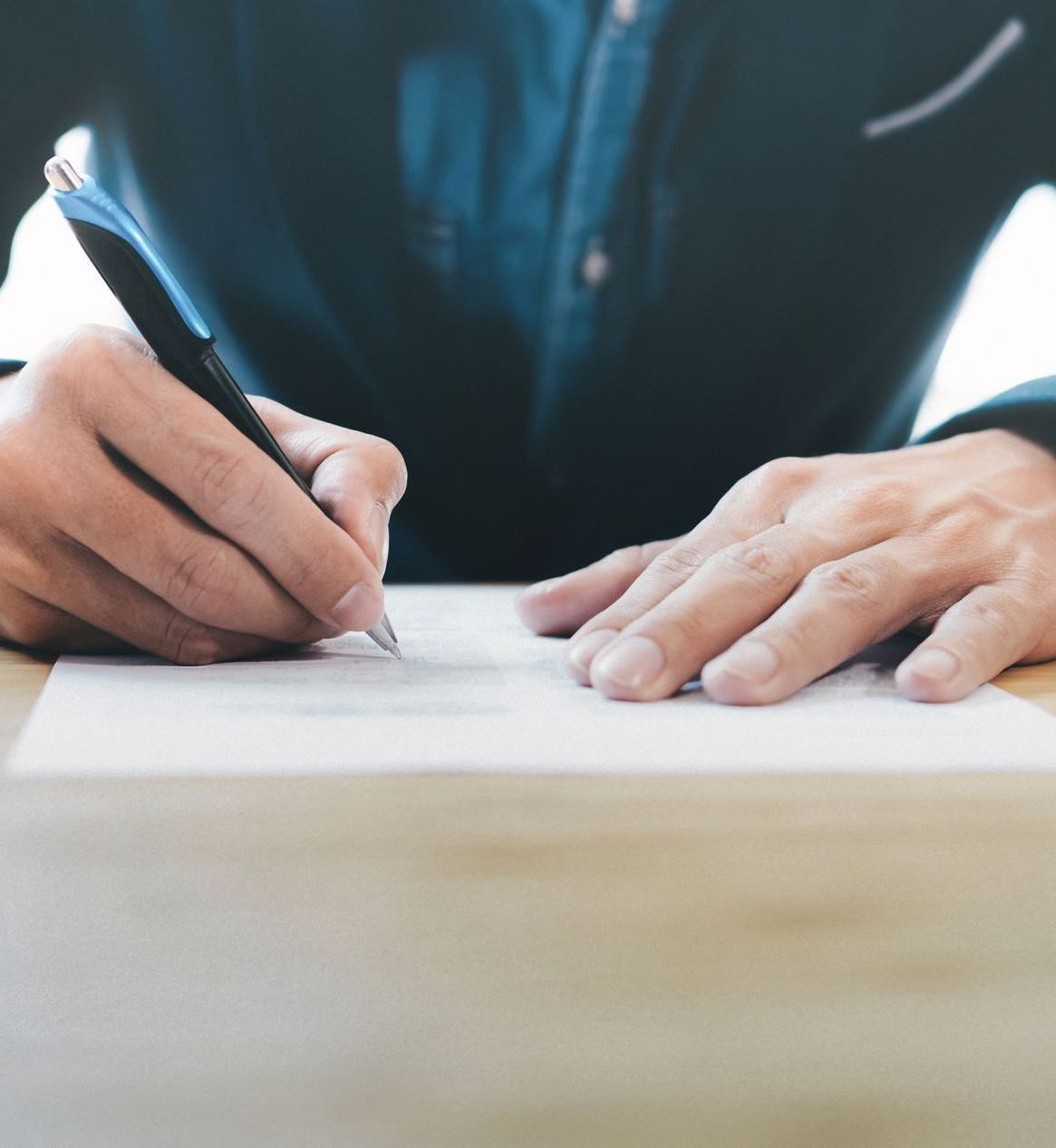 A person is writing on a piece of paper with a pen