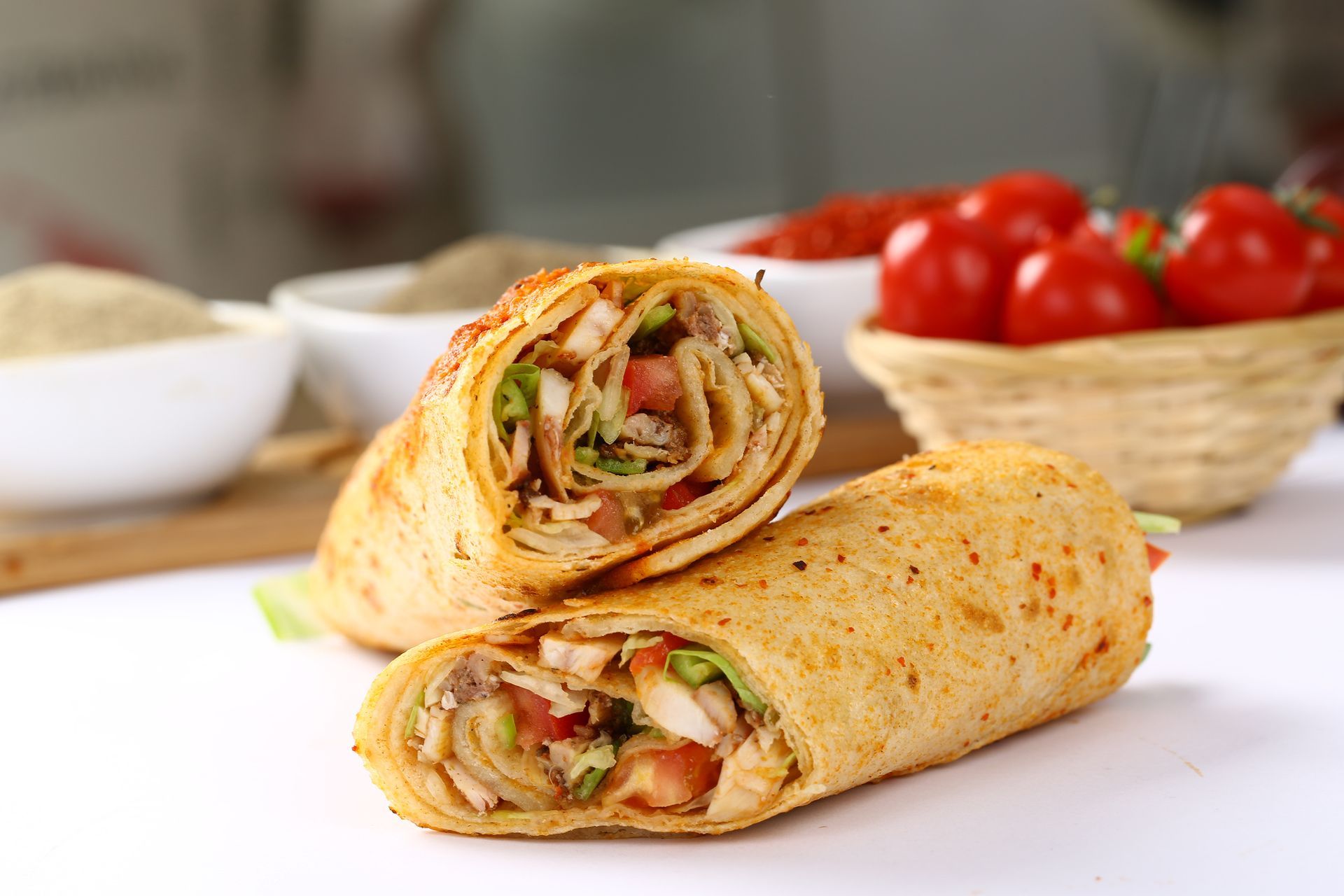 A close-up of a tortilla wrap on a table with tomatoes.