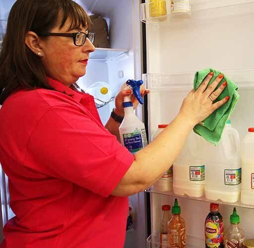Cleaner cleaning inside of fridge in office kitchen