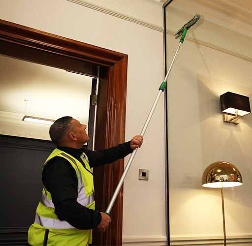 Window cleaner cleaning glass partition in office reception