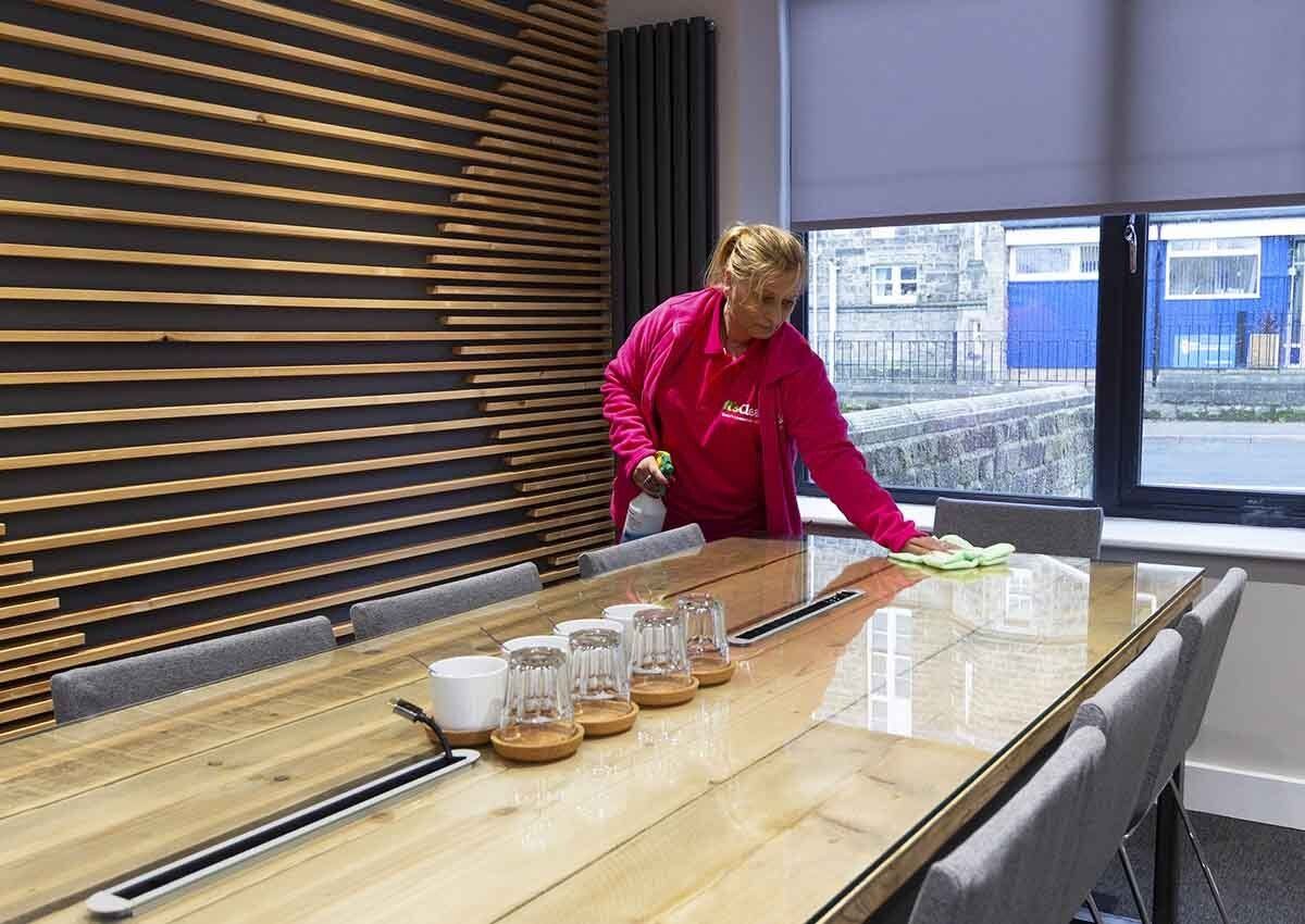 Cleaning glass table top in office meeting room