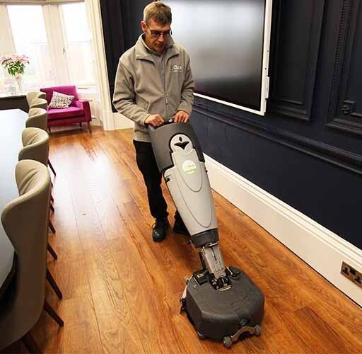 Cleaning office conference room floor with floor scrubber
