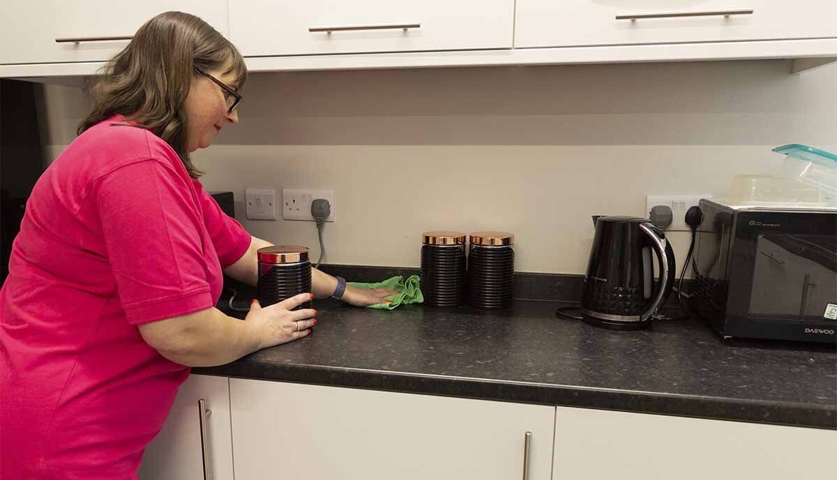 Cleaning office kitchen worktop in Harrogate with green microfibre cloth