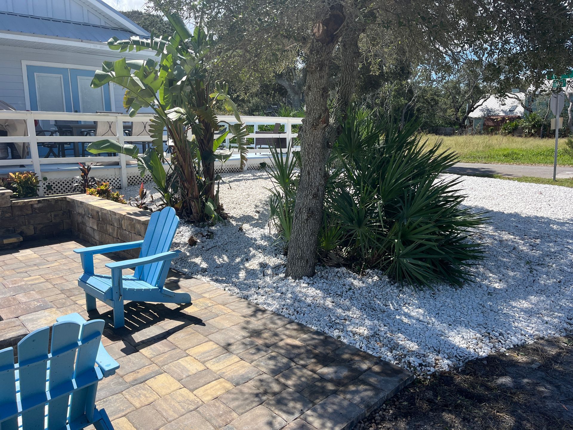 Two blue chairs are sitting on a paver patio in front of a house.