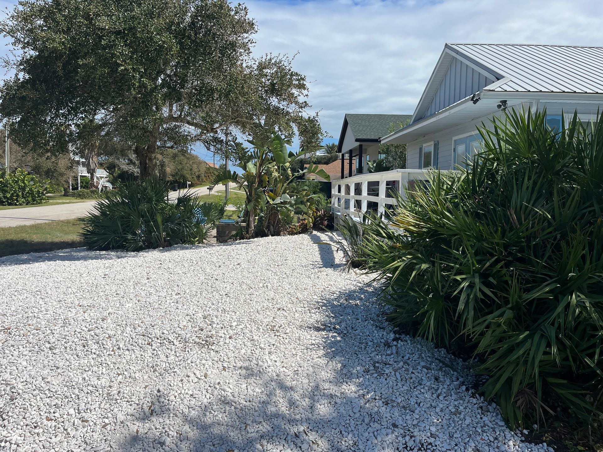 A white house with a gravel driveway in front of it.