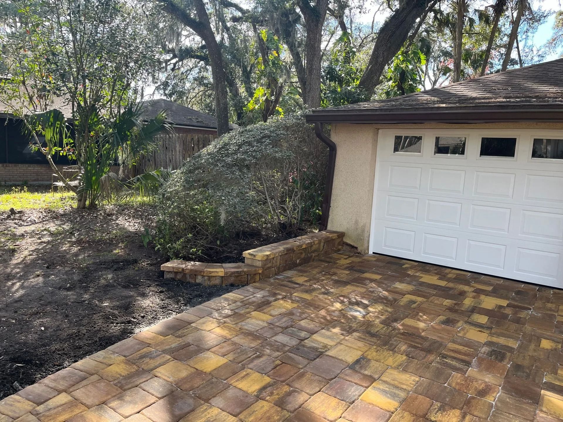 A white garage door is sitting next to a brick driveway.