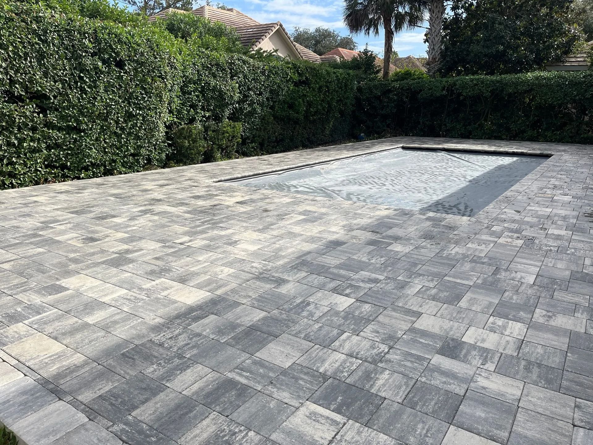 A brick patio with a swimming pool in the background.