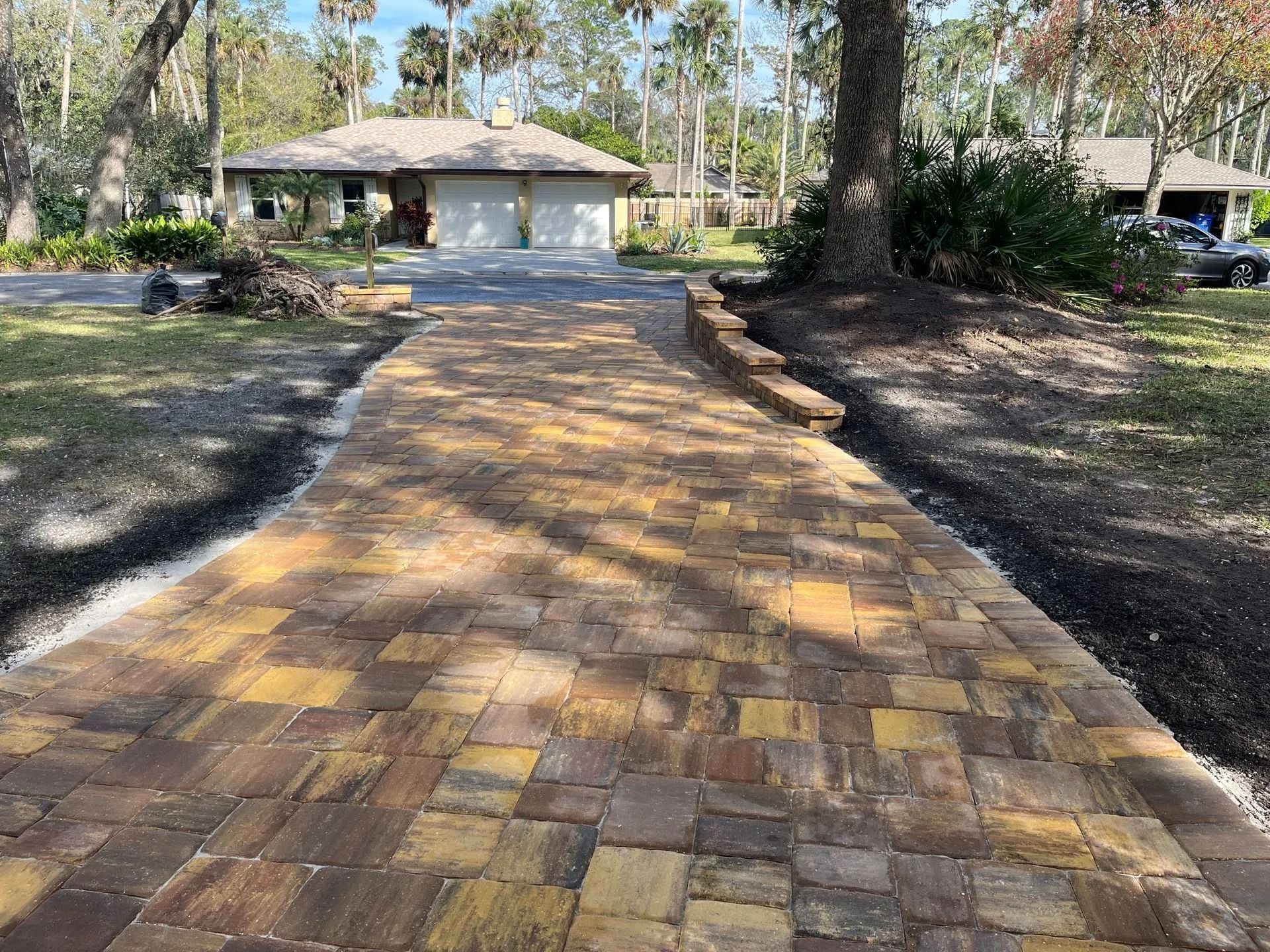 A brick driveway leading to a house with a garage.