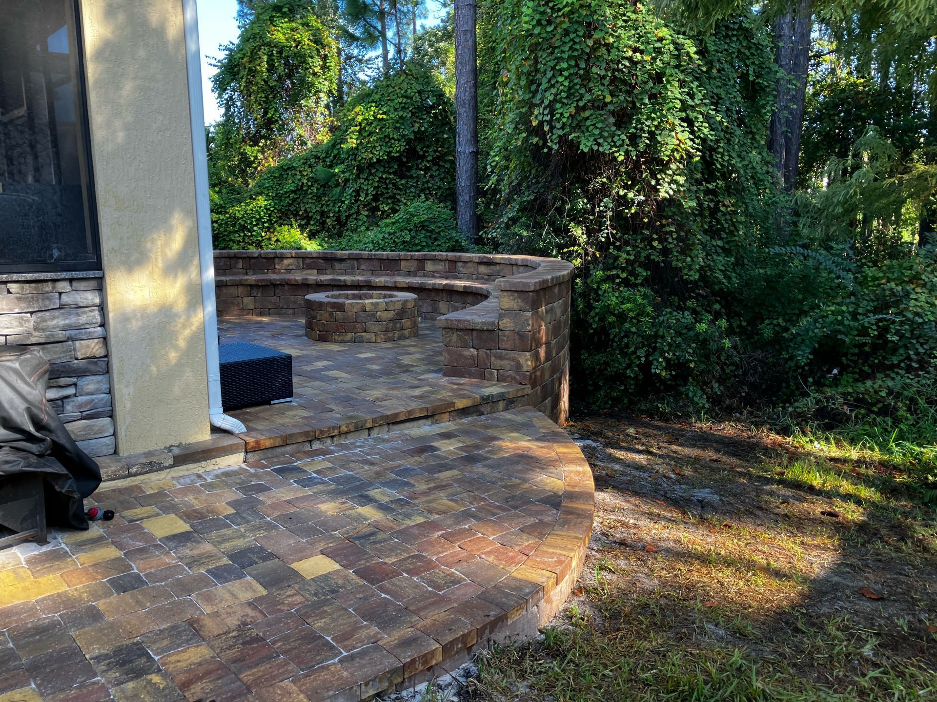 A paver patio with a fire pit in the backyard of a house.