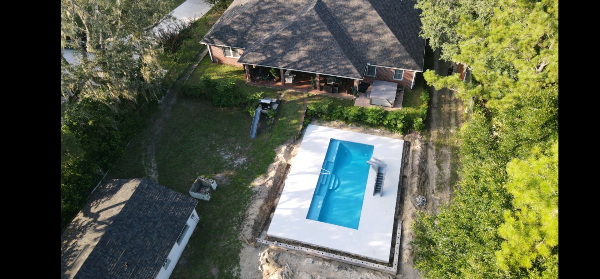 An aerial view of a swimming pool in the backyard of a house.