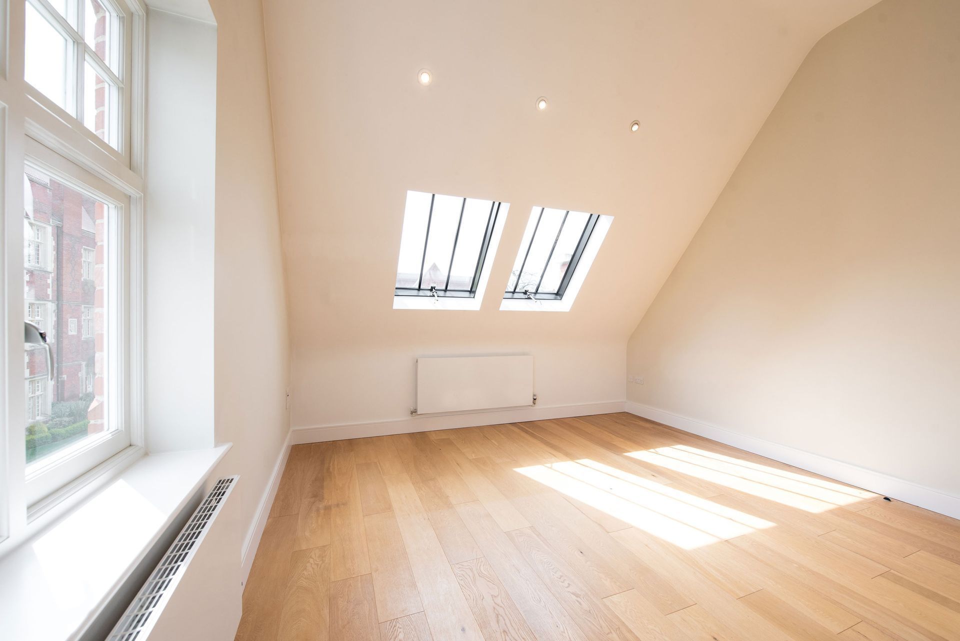 An empty room with hardwood floors and two windows