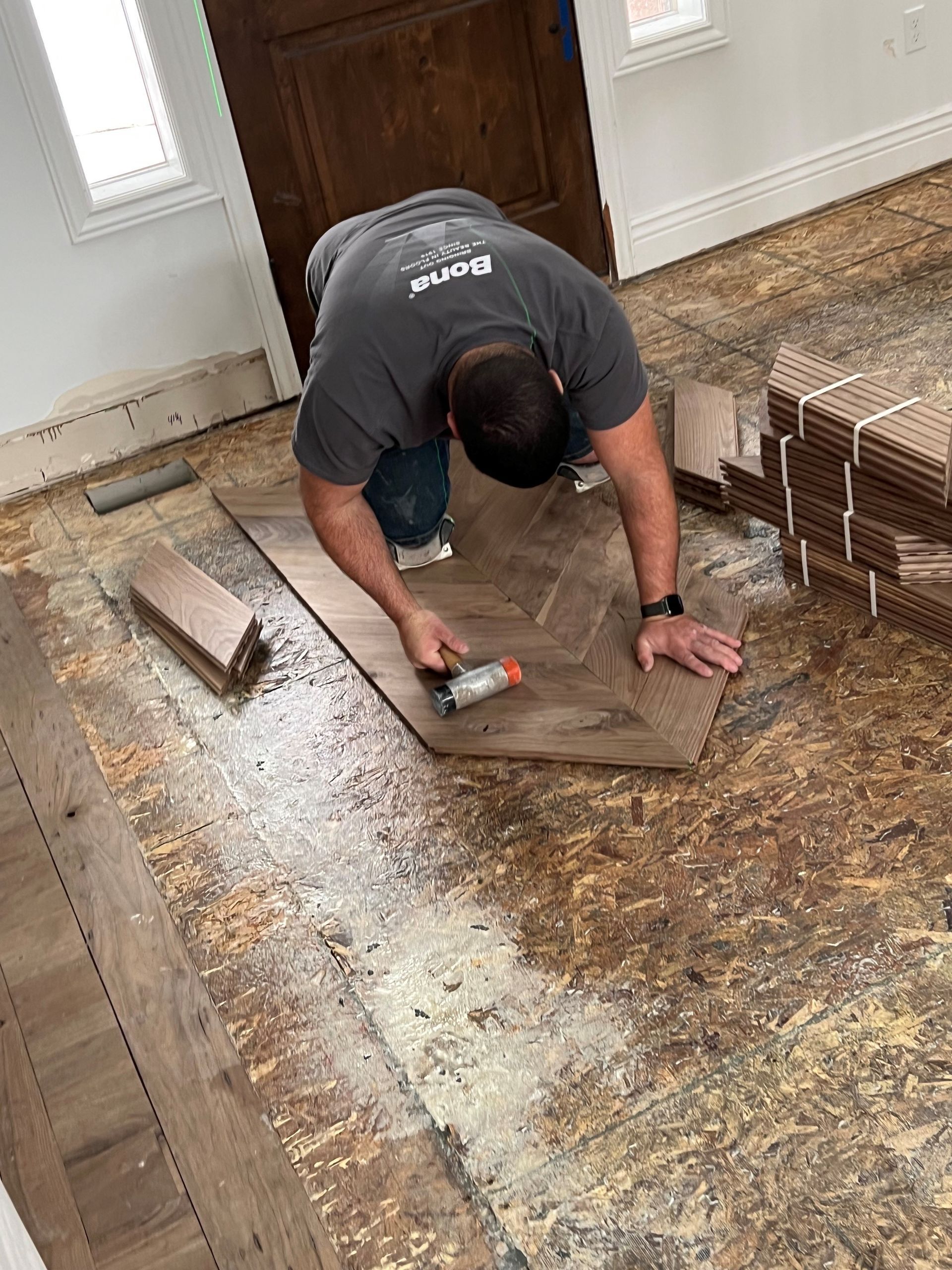 A man is working on a wooden floor in a room.