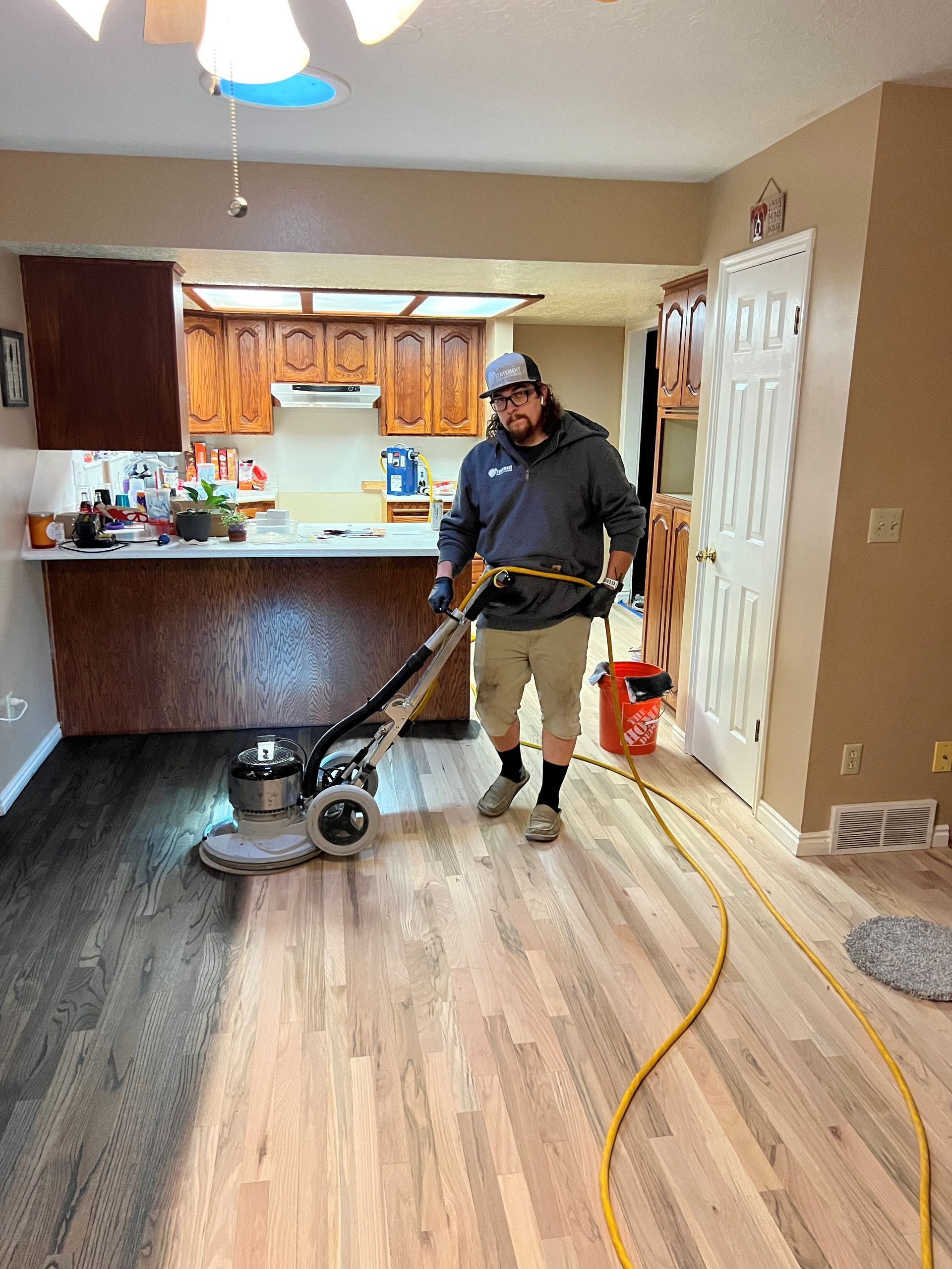 A man is cleaning a wooden floor with a vacuum cleaner.