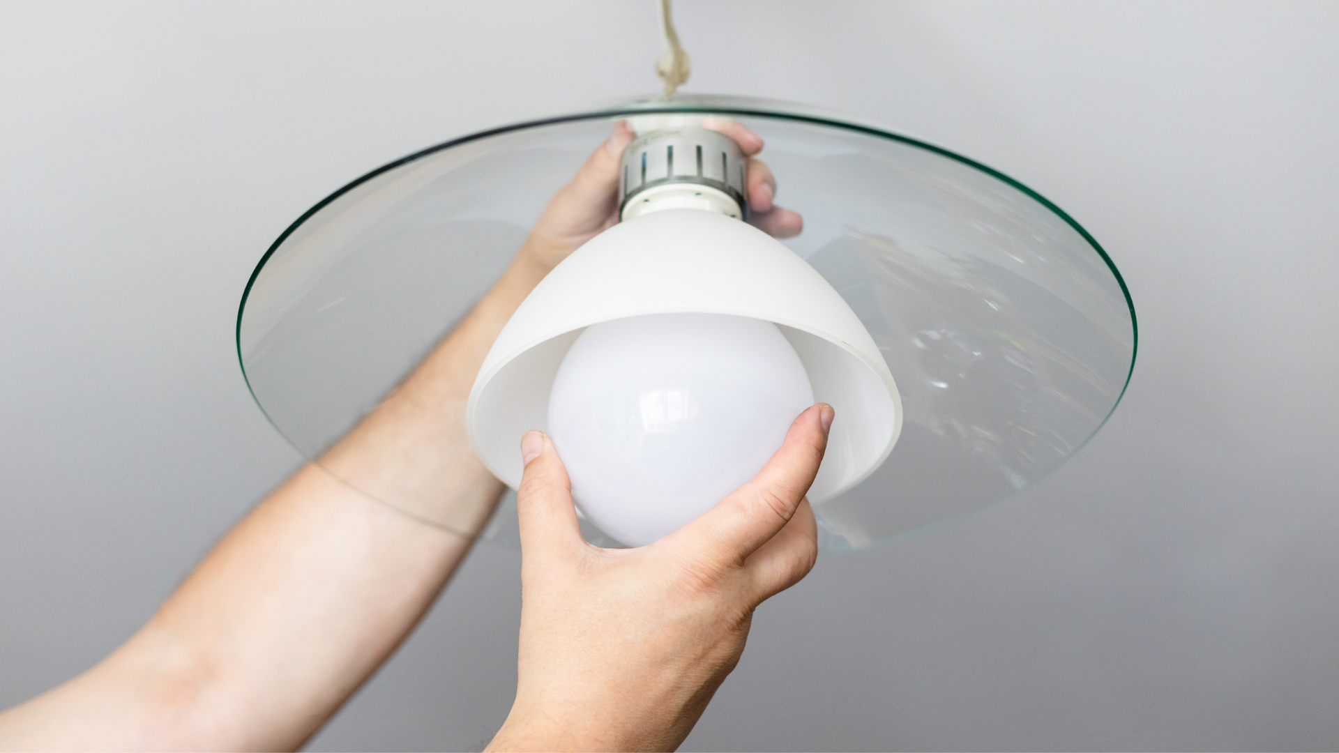 A person is changing a light bulb in a ceiling light.