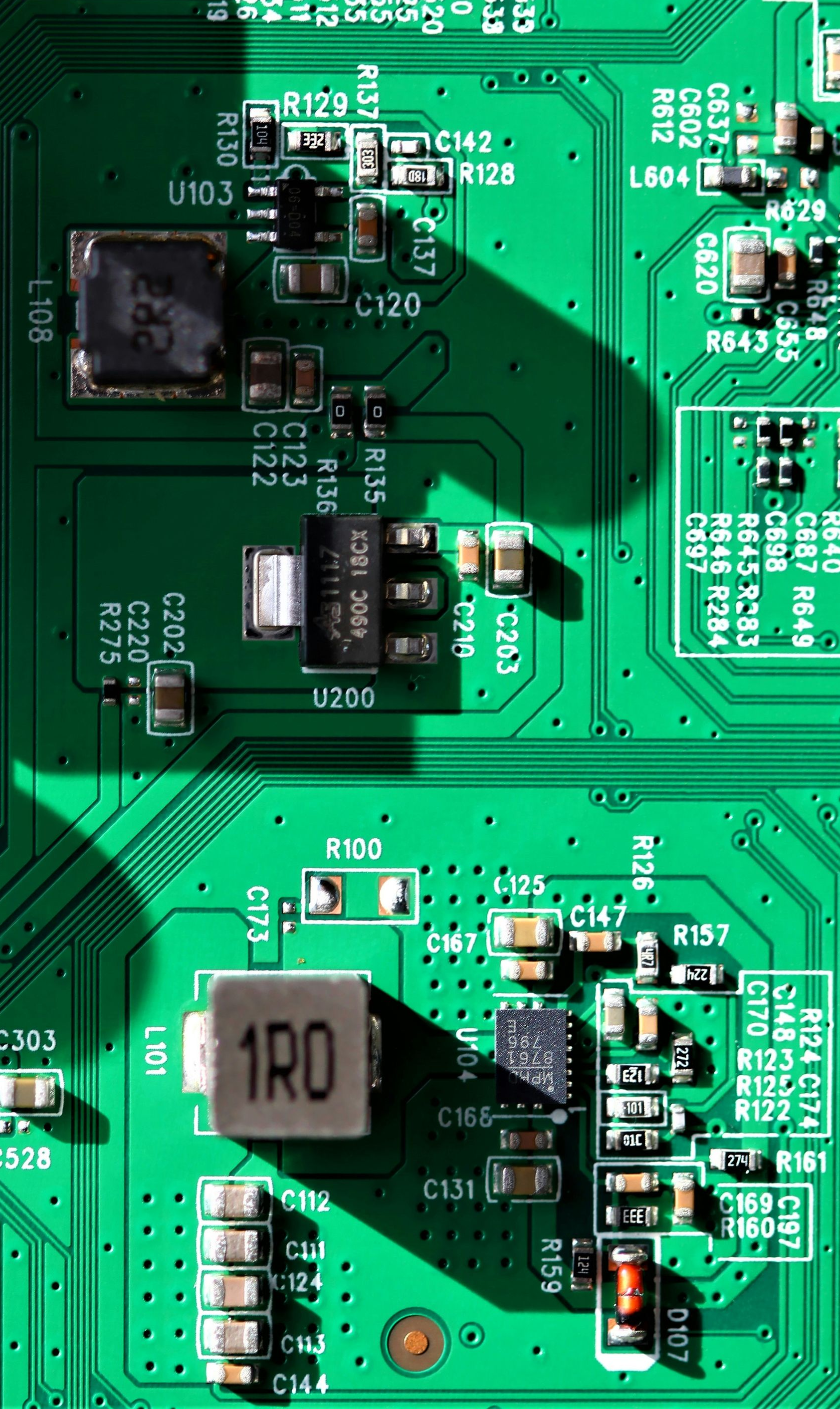 Green circuit board with various electronic components.