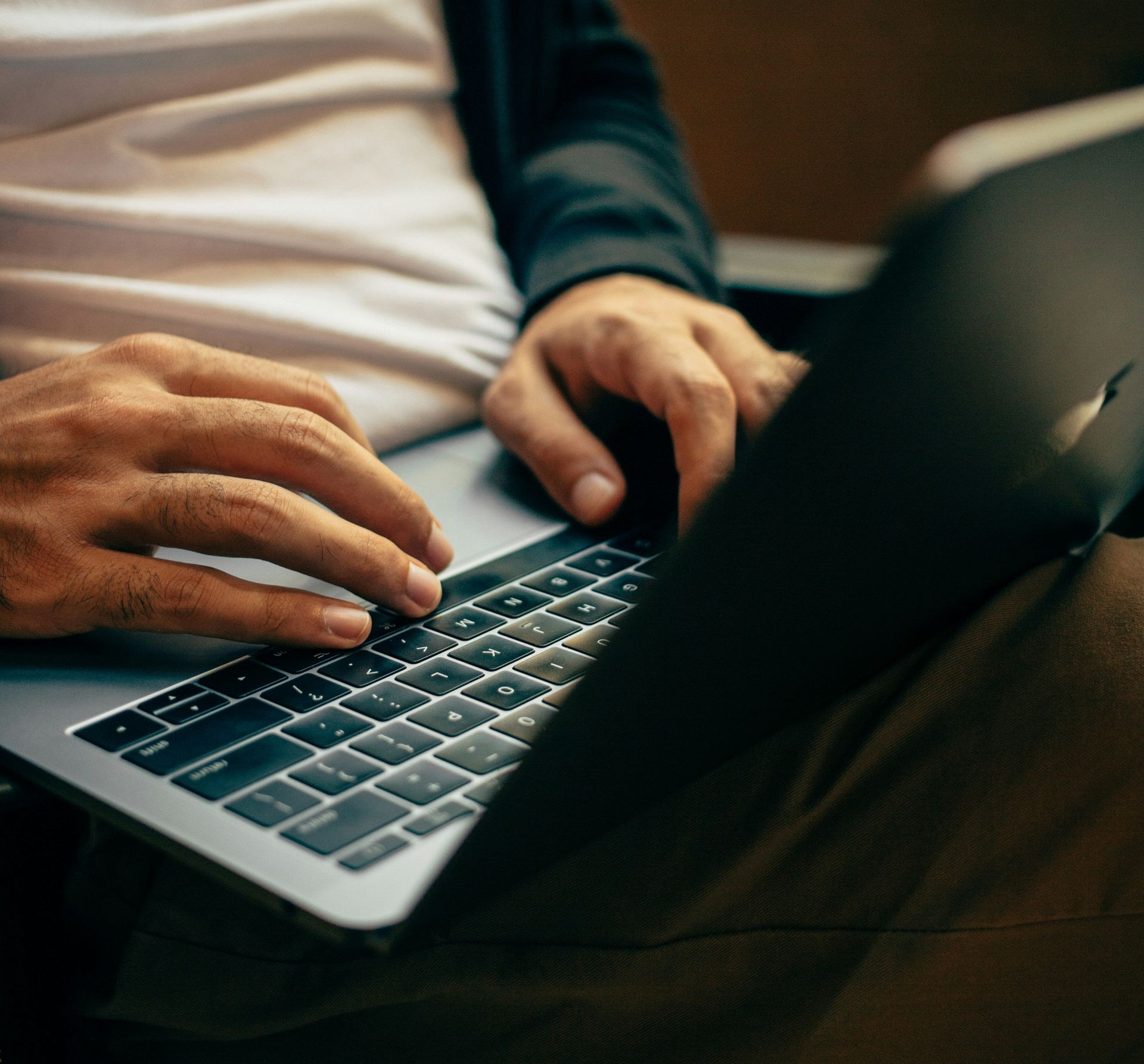 Person using a laptop, typing with both hands. The computer is on their lap.