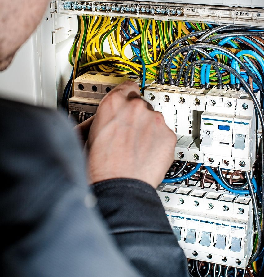 Electrician working on a circuit breaker panel, connecting wires.