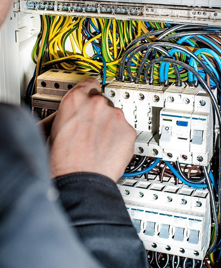 Electrician working on a circuit breaker panel, connecting wires.