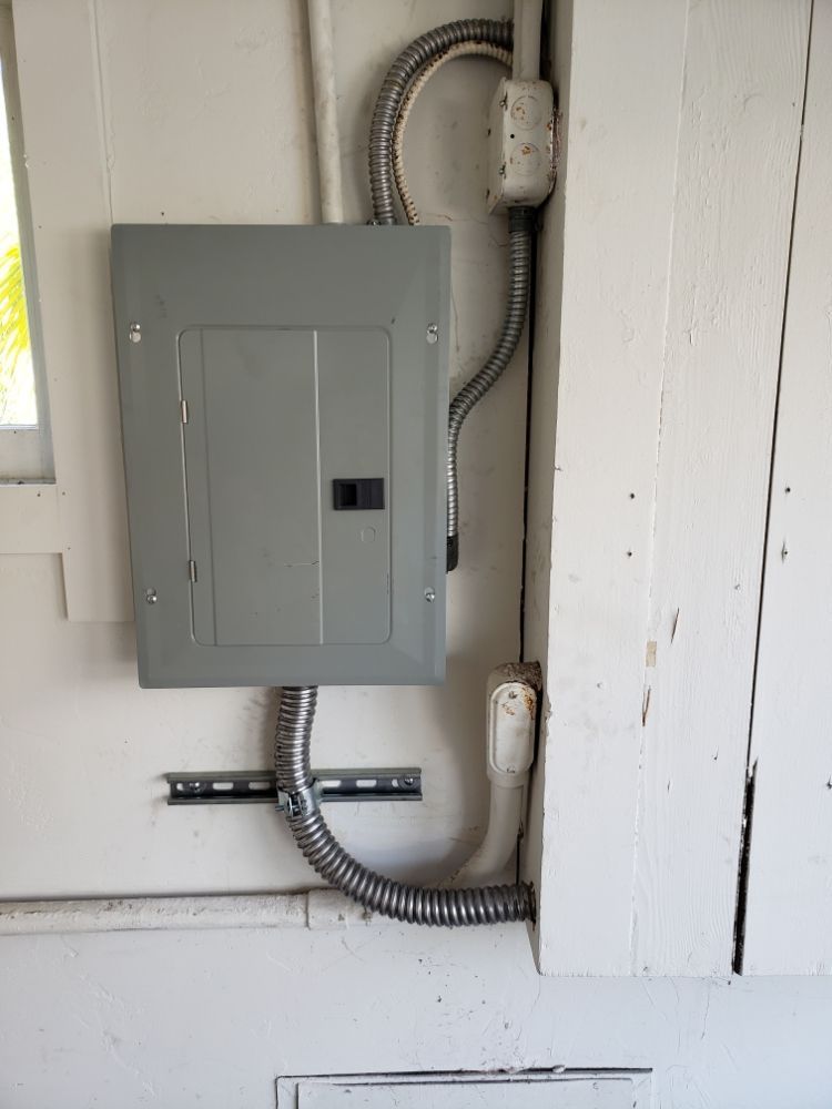 A electrical box is hanging on a white wall next to a window.