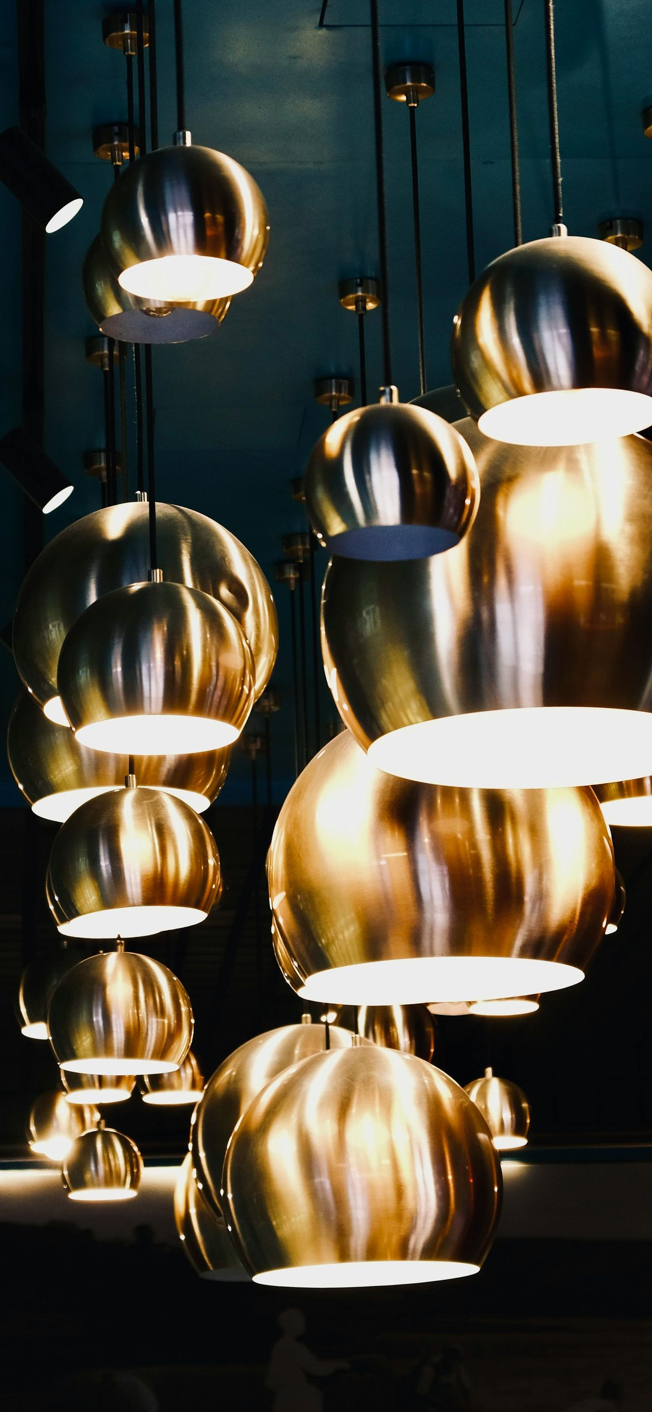 Golden pendant lights hanging from a dark ceiling, illuminating a space.